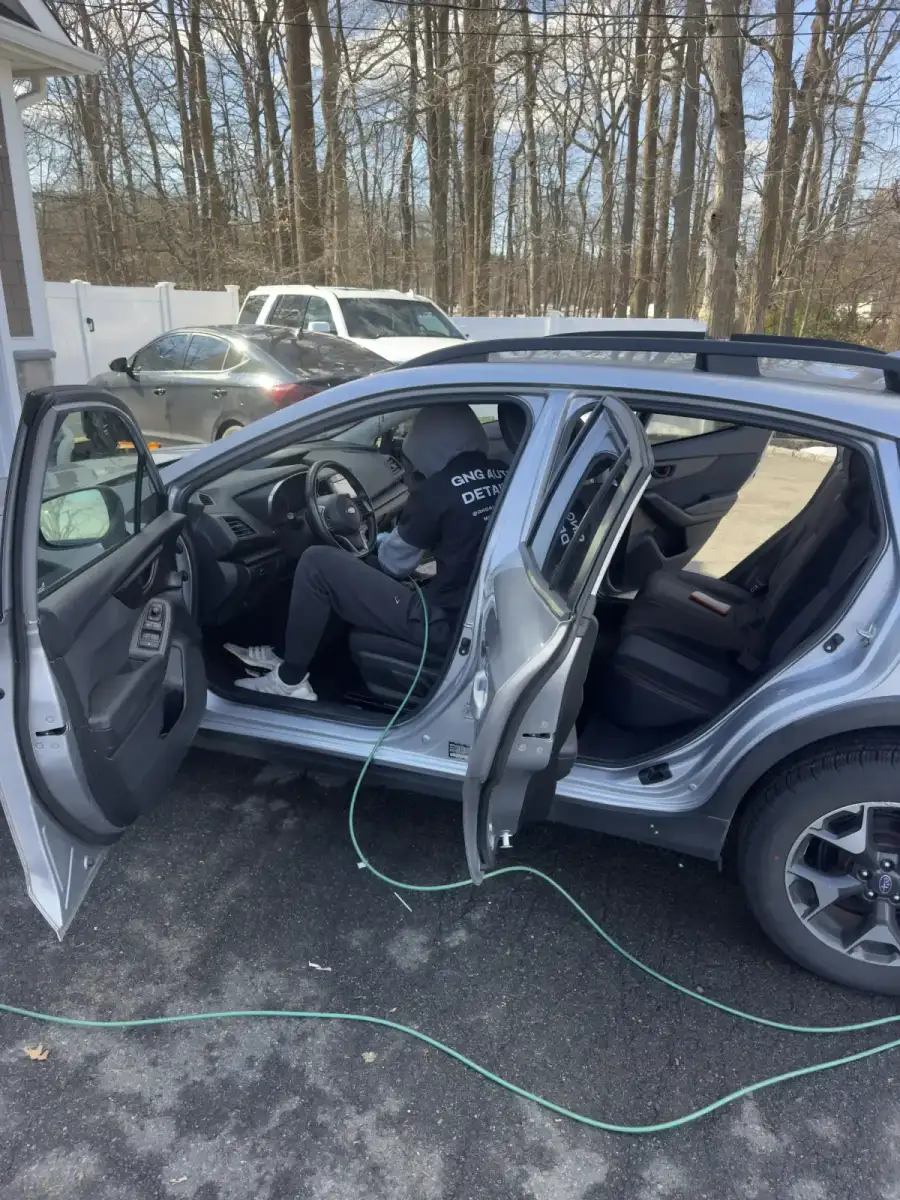 GNG detailer working inside vehicle during interior car detailing service