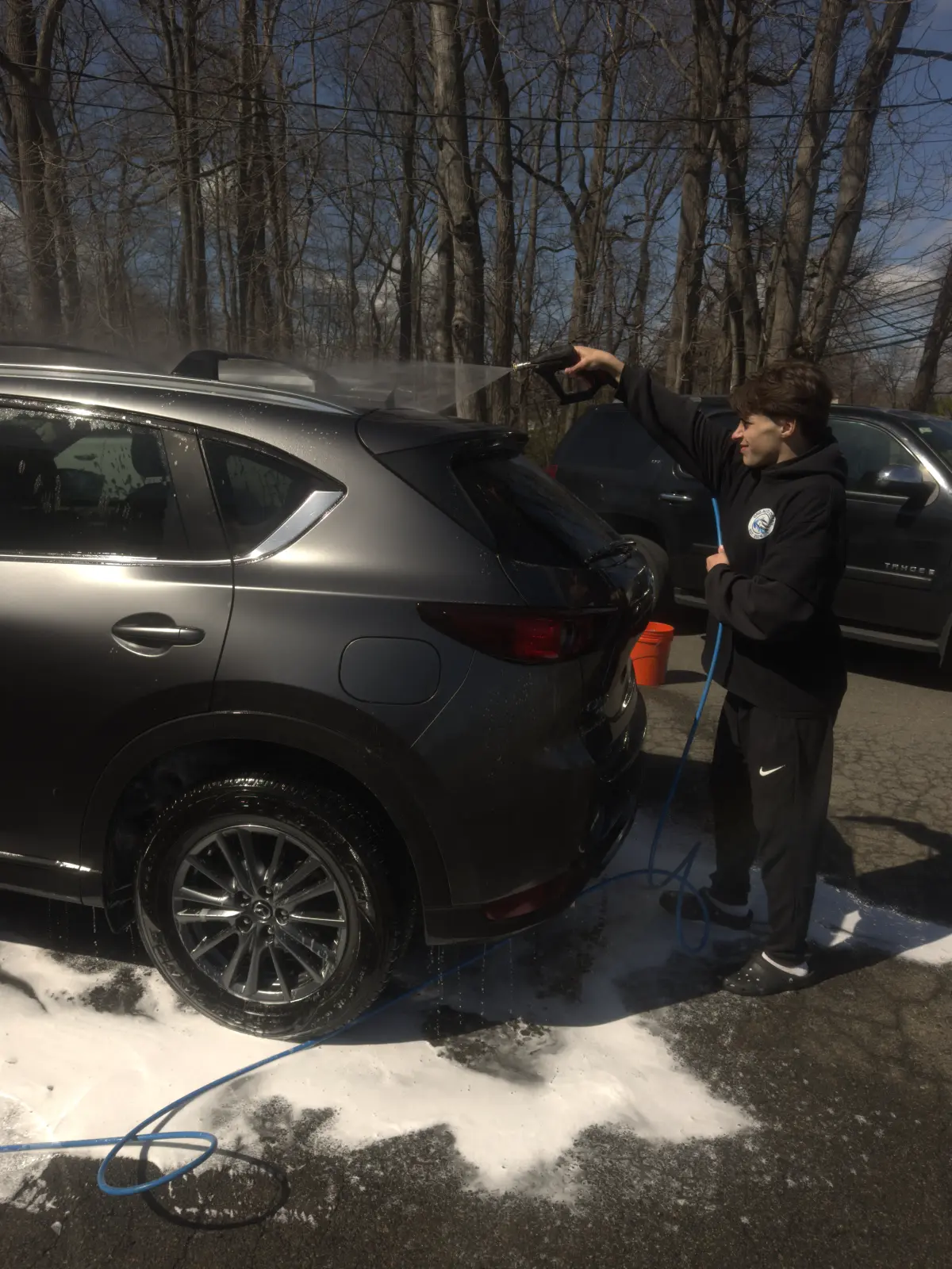 GNG Auto Detail crew member power washing a vehicle exterior on a sunny day in Morris County NJ